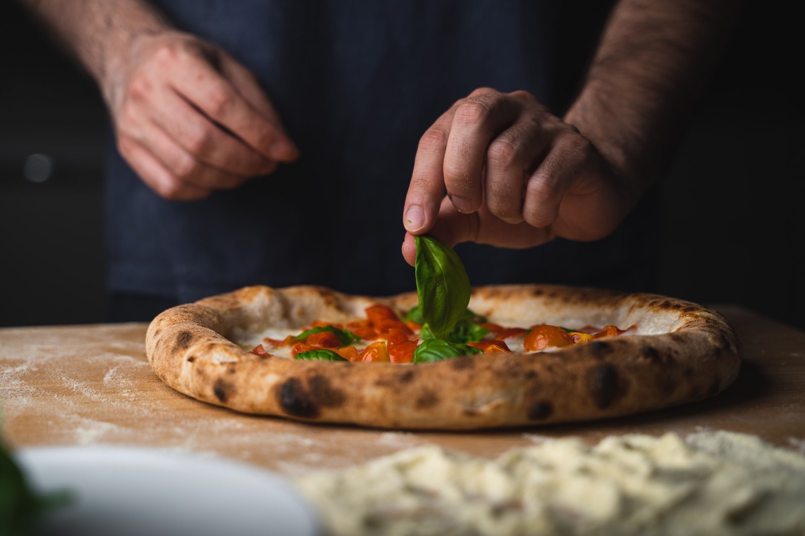 Man placing basil on a freshly baked pizza